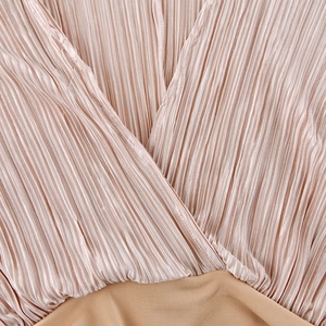 Detailed close-up of V-neckline with pleated pink-beige silky fabric texture