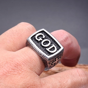 Macro detail of men's vintage stainless steel GOD ring with cross engraving on the side
