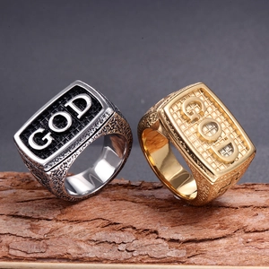 Vintage stainless steel GOD rings in gold and silver finish on a rustic wood base