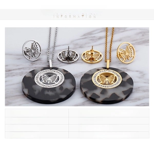 Detail of butterfly necklace and earrings set in gold and steel with zircon accents