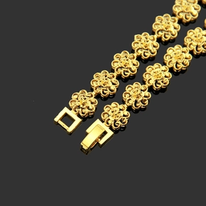 Elegant gold plum blossom bracelet with hollow flower links on black reflective surface