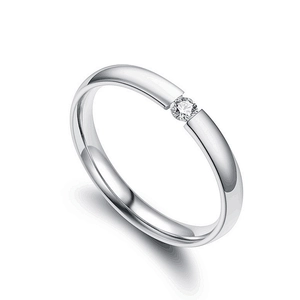 Anello di coppia minimalista in argento con zircone incastonato su fondo bianco studio