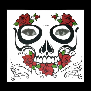 Macro detail of sugar skull face tattoo with red roses and green leaves on paper