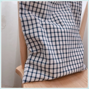 Détail de la texture du tissu à carreaux bleu et blanc sur un sac en coton sur une chaise