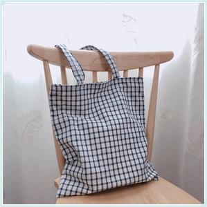 Vue détaillée du sac cabas en coton à carreaux bleu et blanc sur une chaise en bois