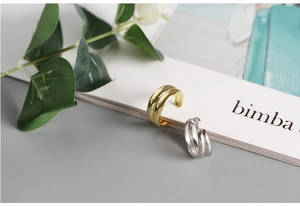 Detail view of minimalist double-layer silver and gold rings on a gray background