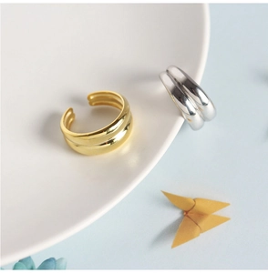 Detail showing minimalist double-layered silver and gold rings on a ceramic plate