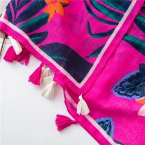 Detailed shot of vibrant tropical leaf prints and colorful tassels on a cotton linen scarf