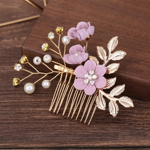 Macro detail of bridal hair comb with purple fabric flowers and pearl accents