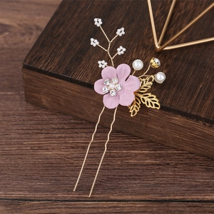 Detailed macro shot of pink fabric flowers and gold leaves bridal hair pin with pearls