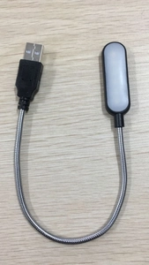 Macro detail of portable black USB LED lamp with flexible metal gooseneck on wood surface