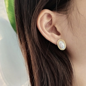 Elegant oval gold-plated silver stud earrings with iridescent shell inlay on model