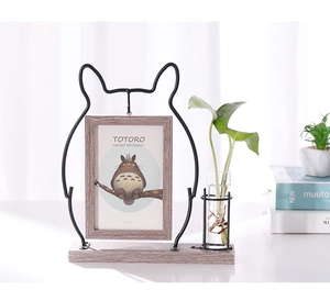 Close-up of cat-shaped iron frame with wooden base and glass hydroponic vase