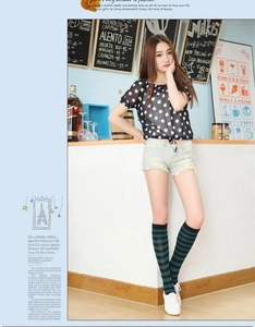 Detail shot of black and green striped knee-high socks worn with denim shorts
