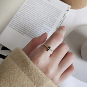 Detail of a minimalist gold ring with a black crystal cross worn on a hand over a book