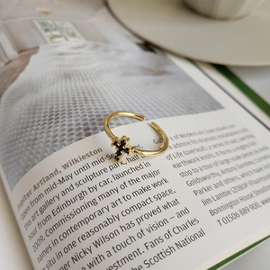 Close-up of a gold cross ring with black crystals placed on an open magazine page