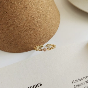 Detail eines goldenen Vintage-Rings mit Hohlmuster und rosa Zirkon auf Kork-Display