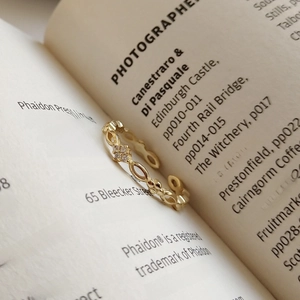 Elegant gold hollow ring with sparkling cubic zirconia on an open book page