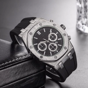 Close-up of silver metal chronograph watch case with black silicone strap and date function