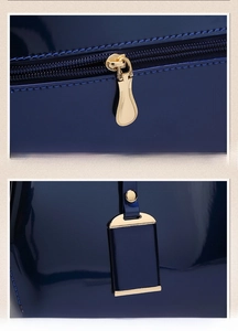 Detail of smooth golden zipper and metal logo charm on a shiny navy patent leather bag