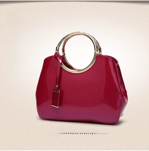 Detail of rose pink patent leather handbag with a round metal ring handle for women
