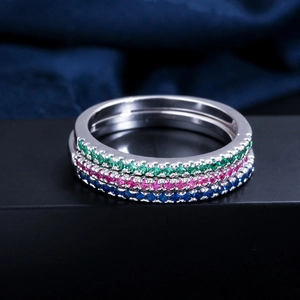 Macro detail of three eternity rings with green, red, and blue micro-set cubic zirconia