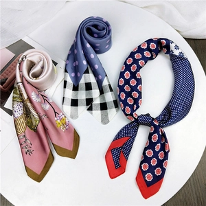 Three elegant twilly silk scarves with floral and polka dot prints in a white tray