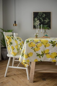 Detailed close-up of lemon print fabric tablecloth on a wooden dining table setup