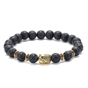 Macro shot of black lava rock beads and golden Buddha head charm on the elastic bracelet
