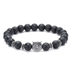 Macro shot of black lava stone beads and antique silver owl head on a beaded bracelet