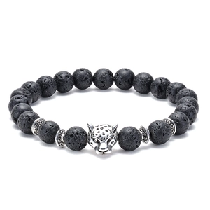 Macro detail of natural black lava rock beads and silver panther head charm on the bracelet