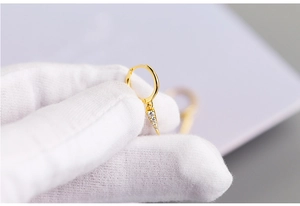 Detailed macro view of a gold cone earring with micro-paved zircons held in white gloves