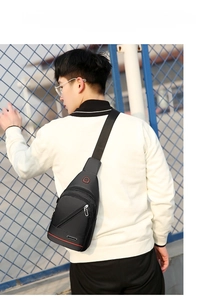 Back view of a black waterproof Oxford cloth sling bag with red trim worn by a male model