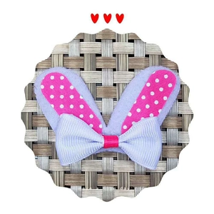 Detail of pink polka dot rabbit ears hair accessory with light purple bow on woven mat