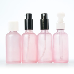 Pink frosted glass spray and dropper bottles set with various caps on white background