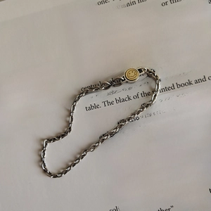 Detailed shot of silver link bracelet with vintage gold smiley face on art book pages