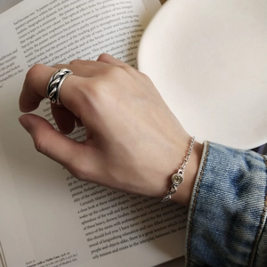 Detail shot of a 925 sterling silver smiley face chain bracelet and a braided silver ring