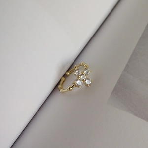 Close-up of golden adjustable clover ring with four sparkling zircons on white paper