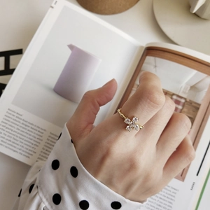 Detail of a minimalist gold ring with four round crystals worn by a model on a magazine background