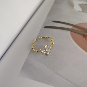 Close-up of golden cross ring with white zircon stones on an artistic background