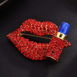 Macro shot of lipstick and red lip brooch with sparkling rhinestones and gold base