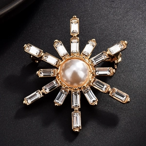 Macro shot of snowflake brooch with gold base, center pearl and clear crystals