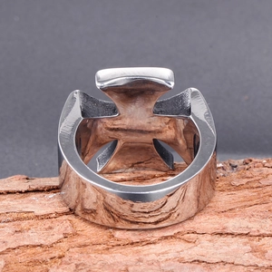 Macro detail of retro stainless steel ring featuring a bold cross design on a textured bark