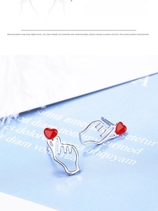 Detail of red heart gesture earrings with silver hooks and enamel finish details