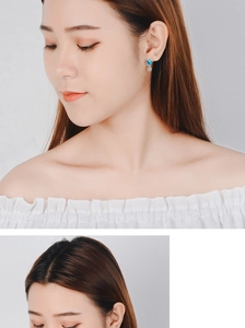 Detailed view of model wearing blue star stud earrings with dangling small crystal star