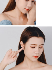 Close-up of model wearing silver heart-gesture earrings with red enamel detailing