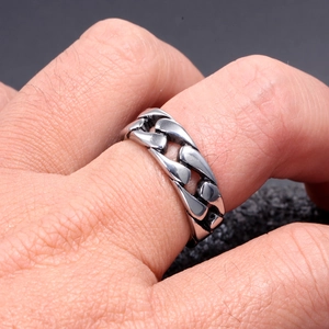 Macro shot of a men's Cuban link chain ring in polished stainless steel on finger