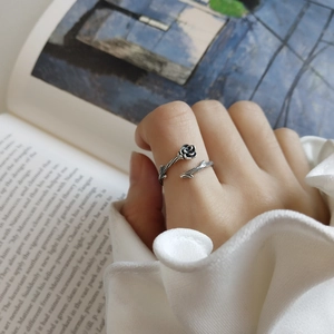 Detailed close-up of a vintage 925 silver black rose ring on a finger with book background