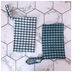 Detail of green and white plaid fabric phone pouches with sturdy wrist straps and neat stitching