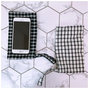 Close-up of small gingham fabric phone pouches with wrist straps on marble tiles